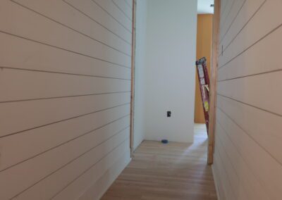 Shiplap hallway with wood flooring running through