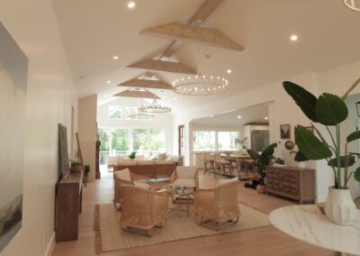 Vaulted great room with exposed beams and white oak flooring after renovation