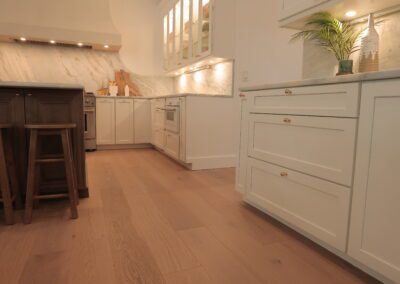 Renovated kitchen with white cabinetry and wood flooring