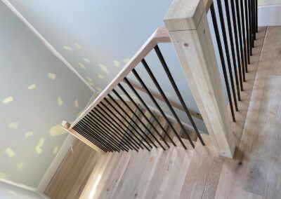 Wood-look floor at the top of a staircase with metal balusters