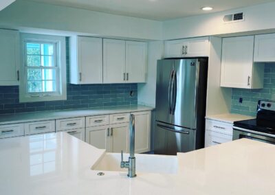 Renovated kitchen with white cabinetry and glass tile backsplash