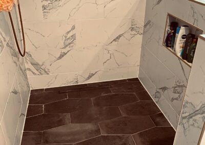 Dark tile floor laid on the diagonal beside marble-look walls