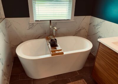 Freestanding tub against marble-look tile walls