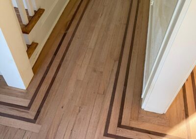 Hardwood floor with a contrasting border inlay at the stair