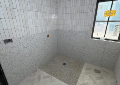 Marble-look tile shower with a herringbone floor inset
