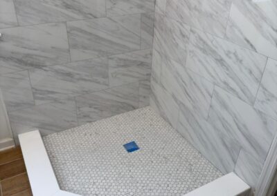 Marble-look tile shower with a corner pan being set