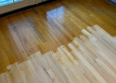 Hardwood floor mid-refinish, sanded boards catching the light