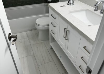 Remodeled bathroom with double vanity and tiled tub surround