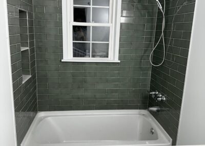 Green tile tub surround with a white-framed window