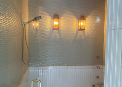 Glass walk-in shower with warm lighting and full-height tile