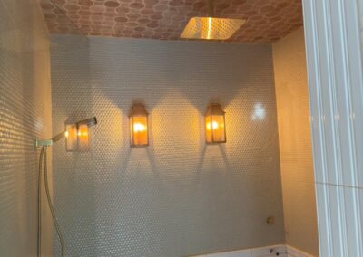 Walk-in shower with wall sconces and a copper-toned ceiling detail