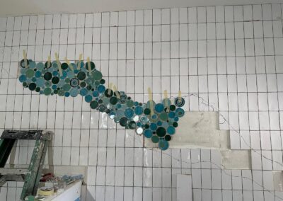 White tiled wall with a flowing teal mosaic accent
