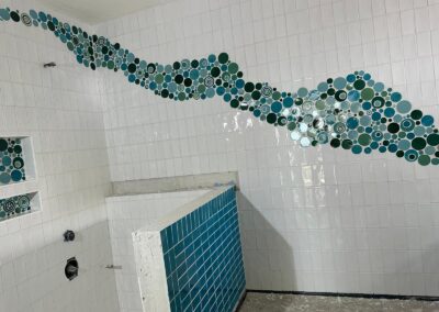 Glass mosaic border set into a white tiled bathroom wall